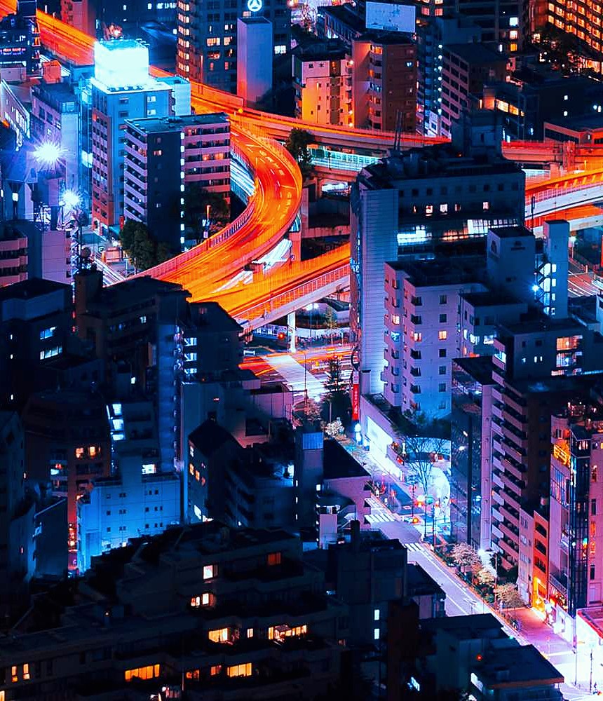 A city lit up at night, traffic tracing bright lines through the streets